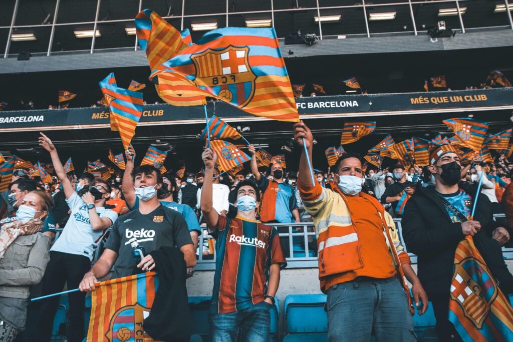 Fans enthusiastically wave FC Barcelona flags at a football match, showcasing team spirit and unity.
